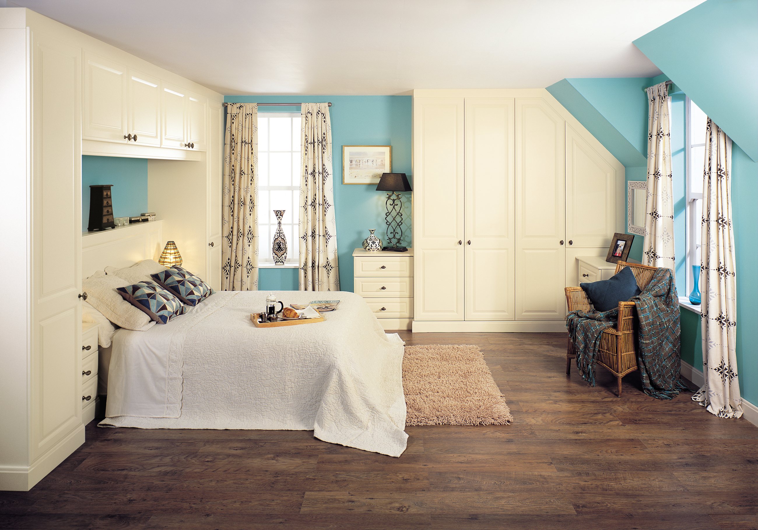 A cream fitted bedroom with wardrobes built around a window and a bed recess