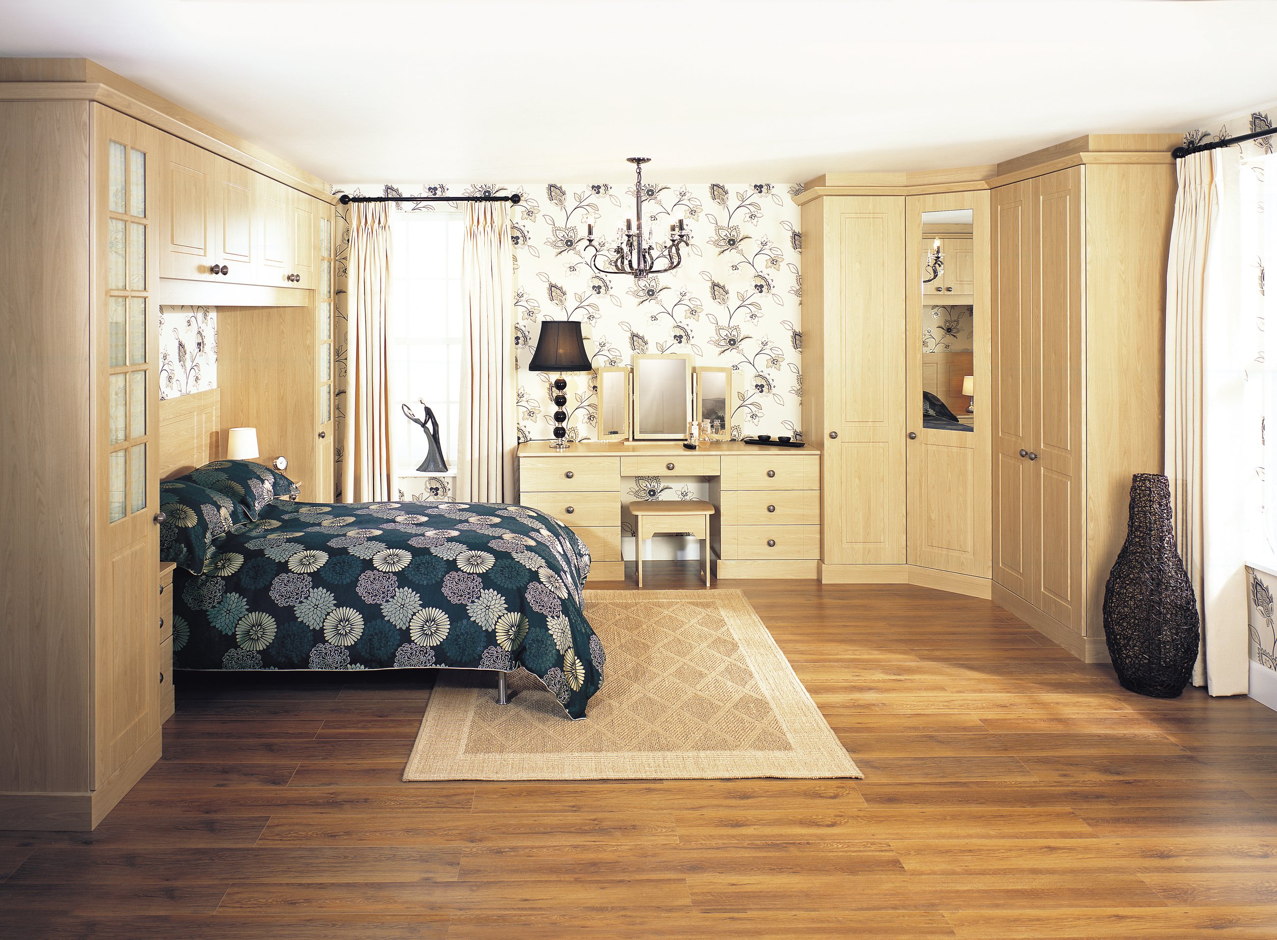 An oak fitted wardrobe run along a bedroom wall with a dressing area