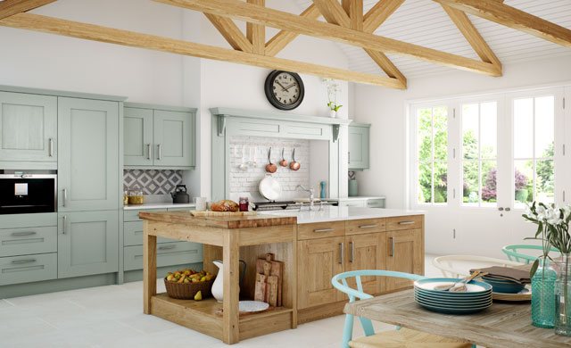 A sage green in-frame kitchen with an oak island and exposed roof beams