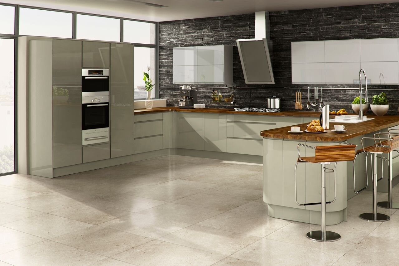 A cream handleless kitchen with a curved island and integrated ovens